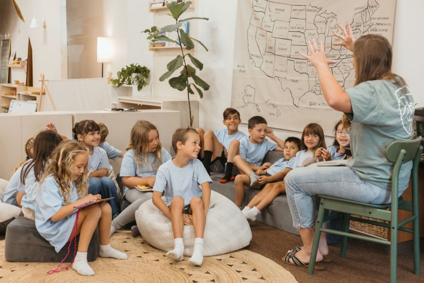 A Legacy teacher tells a story with big hand gestures to students gathered on cushions and a bean bag